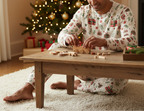 South Asian man wearing Christmas Present pajamas while assembling a wooden toy