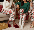 Diverse group of women wearing Christmas tree pajama pants in a cozy indoor Christmas lounge