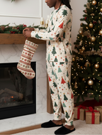 Man with locs wearing Blue Christmas all-over print pajamas with fitted same-fabric ankle cuffs while hanging a stocking