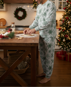 Latino man wearing a pocketless green snowflake long sleeve crew neck pajama set with matching cuffed pants while preparing Christmas cookies