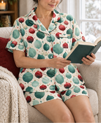 A woman reading by a window in the ivory ornament-print short-sleeve pajama top and matching pajama shorts.