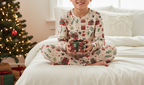 East Asian child wearing Christmas present leggings with a matching printed top in a holiday bedroom