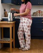Woman making tea wearing Red Snowflake pajama pants and a rose lounge top