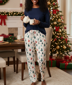 Black woman wearing the Blue Christmas women’s pajama pants while pouring hot cocoa in a festive dining room