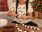 Child wearing Spring Christmas kids pajama top while threading a popcorn garland
