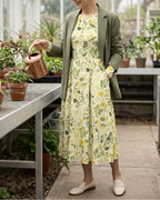 Yellow floral midi dress with a sage jacket in a greenhouse
