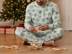 South Asian man wearing Green Snowflake pajamas while assembling a wooden toy