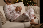Middle Eastern man in pocket-free red snowflake pajamas relaxing with a holiday movie