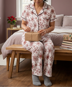 Woman opening a gift wearing Red Snowflake pajama pants and matching black-trim shirt