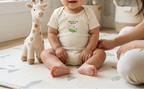 Baby wearing cream New to the Patch flower onesie in a nursery setting.