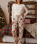 East Asian woman wearing the Christmas Present women’s pajama pants in a festive bedroom