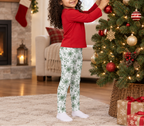 Child wearing Green Snowflake kids leggings while decorating a Christmas tree