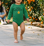 Toddler wearing green Baby Gardener Orange Onesie in a citrus garden