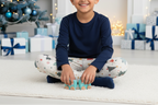 South Asian child wearing blue Christmas leggings with a navy top in an indoor Christmas playroom