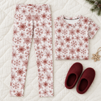 Red Snowflake kid pajama leggings on a quilt with folded matching shirt and slippers; shirt sold separately