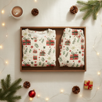 Folded Christmas Present men’s pajama top and matching pocketless pants in a wooden split tray with cocoa, greenery, gifts, and warm lights