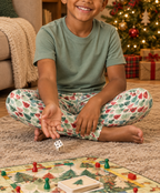 Boy in Leafy Dreams leggings playing a board game by the Christmas tree