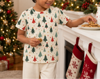 Child wearing a Christmas tree pajama top while placing cookies by a decorated mantel