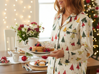 White woman wearing the Spring Christmas women’s long sleeve pajama top while serving a festive holiday breakfast