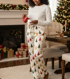 Black woman wearing the Spring Christmas women’s pajama pants while pouring hot cocoa in a festive dining room