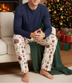 Blond man wearing Christmas Present men’s pajama pants with a solid navy shirt in a Christmas living room