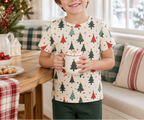 Child wearing a Christmas tree pajama top and holding cocoa in a holiday breakfast nook
