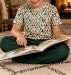 Boy in Leafy Dreams pajama top reading by the fireplace