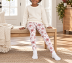 Child wearing Red Snowflake kid pajama leggings sitting on a holiday entryway bench