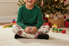 Latino child wearing Christmas present leggings with a green top in a Christmas family room