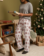 Woman choosing a board game wearing Red Snowflake pajama pants and a gray lounge top