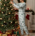 South Asian man wearing a matching green snowflake long sleeve crew neck pajama set while decorating a Christmas tree
