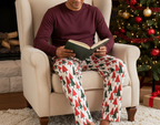 Unique Hispanic man wearing Christmas Tree men’s pajama pants with a burgundy shirt in a holiday reading corner