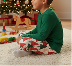 Latino child wearing Christmas tree leggings with a green top in a Christmas family room