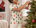 Child wearing a Christmas tree pajama top while decorating a holiday tree