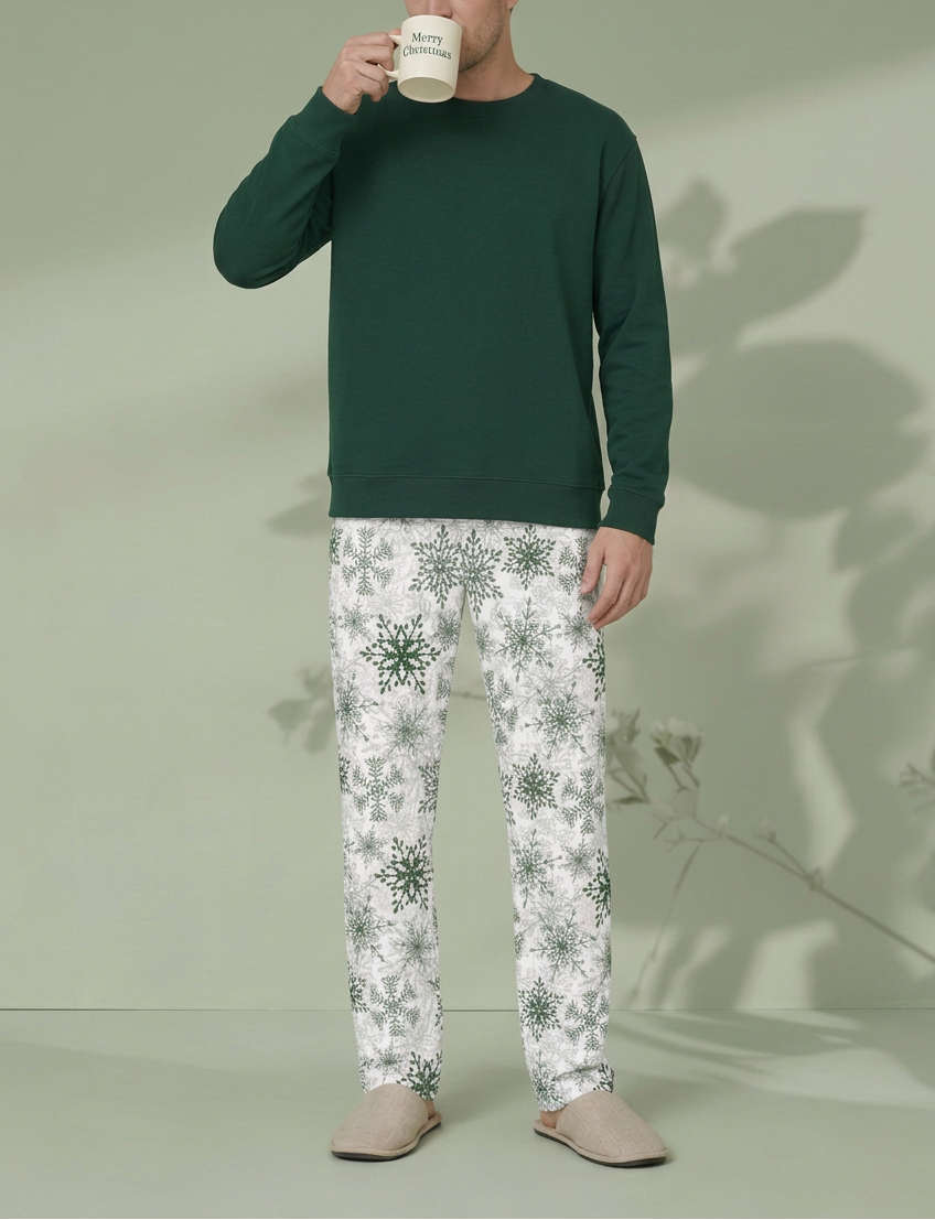 Man sipping from a Merry Christmas mug in Green Snowflake pajama pants