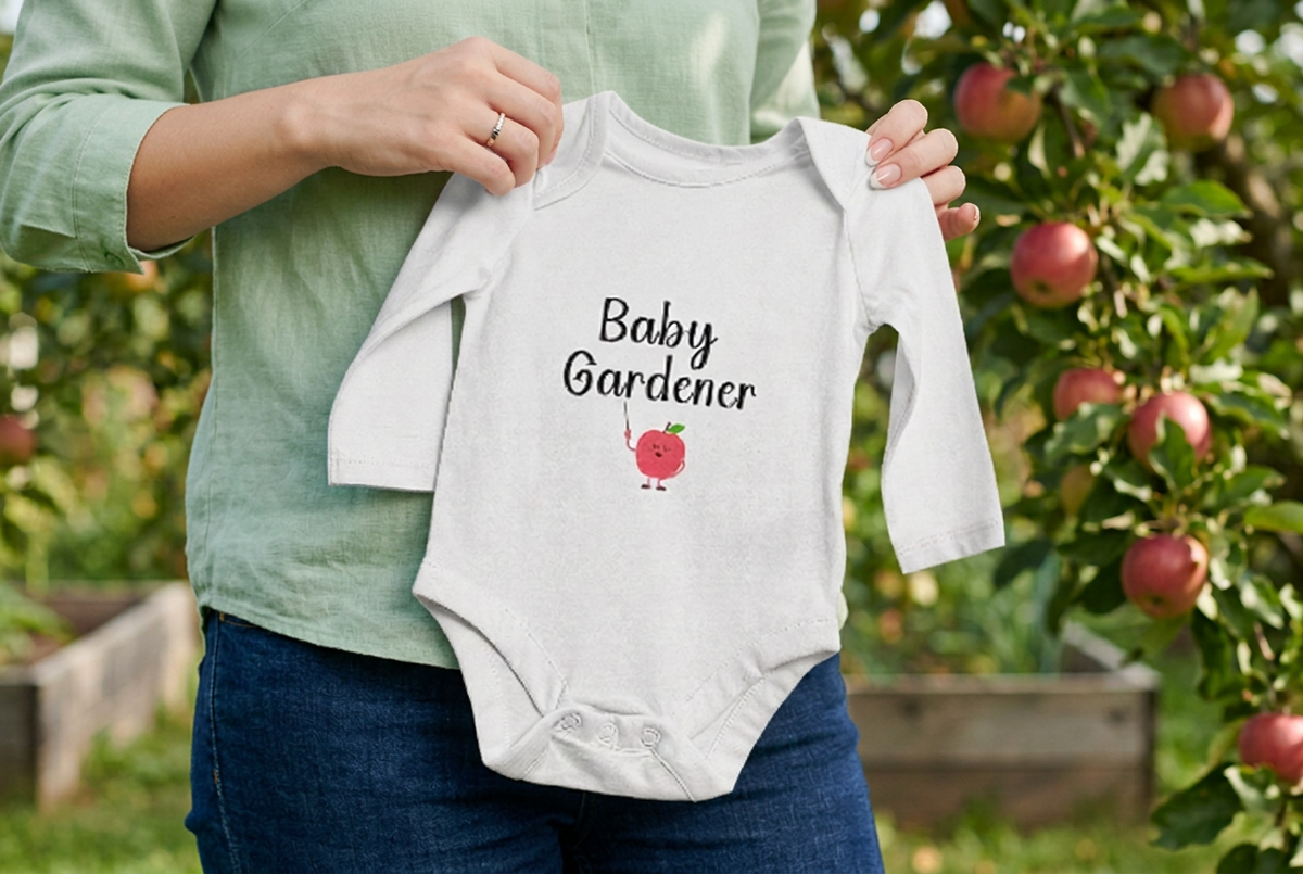 Mom in pastel green blouse and dark jeans holding the apple onesie