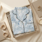 Soft blue pajama top folded square in cream gift box, sleeves fully hidden
