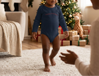 Toddler boy walking in the Navy Happy Holidays onesie