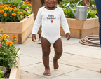 Toddler girl in white beside vegetable beds