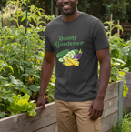 A man wearing a dark gray graphic t-shirt that reads 'Daddy Gardener' with illustrations of vegetables, standing in a garden next to a wooden planter.