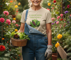 A smiling senior woman in a garden holds a wooden basket filled with fresh lettuce. She is wearing a beige graphic T-shirt that reads 'GARDENING GRANDMA' with a leaf illustration, blue denim overalls, gardening gloves, and a headband.