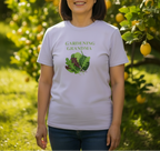 A woman wearing a light lavender graphic t-shirt with the words 'GARDENING GRANDMA' and a green leaf illustration, standing in a sunny garden with lemon trees in the background.